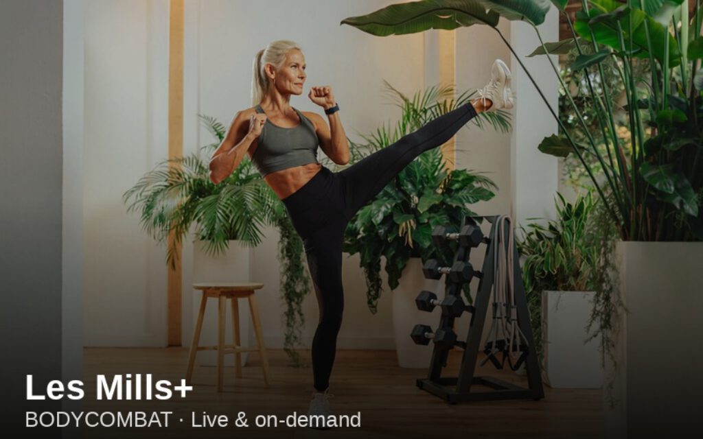 Woman performing BODYCOMBAT high kick — Les Mills+ cardio workout at home
