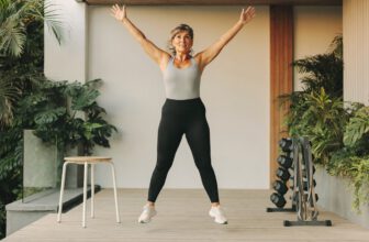 Woman in 40s doing jumping jacks as part of her HIIT workout