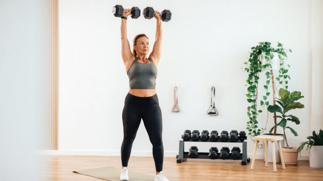 Perimenopausal woman in her late 40s doing upper body workout using heavy dumbbells