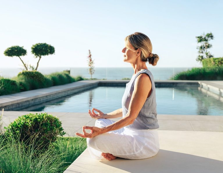 A woman meditating at the pool